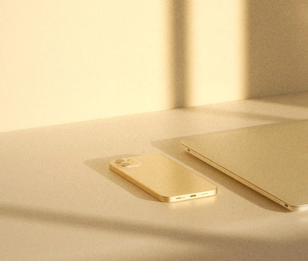 A phone and a laptop on a desk, in golden light